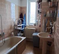 A bathroom in a family house with light tiles, a bathtub, and a sink.