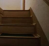A staircase with a wooden railing in a family house, illuminated by a ceiling light.