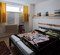 A bedroom in a family house with a carpet, a bed, and yellow curtains.