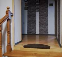 A staircase in a family house with a wooden railing and a decorative wall.