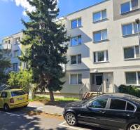 An apartment building in Bratislava on Nezábudkova Street among trees and parked cars.
