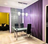 Dining area in a 2-room apartment with purple walls and a glass table.