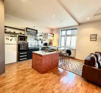 A kitchen with a bar counter and wooden flooring in a 2-room apartment.
