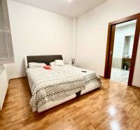 A bedroom with a bed and wooden floor in a 2-room apartment.