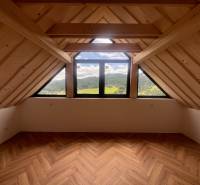 Attic space in a cabin with mountain views and wooden beams.
