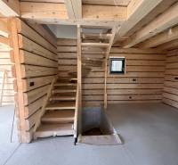 Wooden interior of a cabin with a concrete floor and staircase.