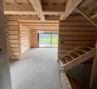 A cabin with a wooden interior, staircase, and glass view of the surrounding nature.
