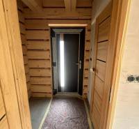 A wooden hallway in a cabin with dark doors and an exposed light bulb on the ceiling.