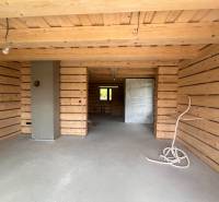 A wooden interior of a cabin with a concrete floor and unfinished elements.