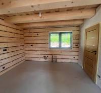 The interior of a cabin with wooden walls, a window, and simple lighting.