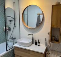 A bathroom in a 4-room apartment with a wooden sink and a round mirror.
