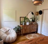 Elegant room with a light armchair, wooden dresser, and houseplants in a 4-room apartment.