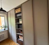 A wardrobe in a 4-room apartment with wooden flooring and shelves for storage.
