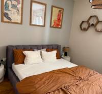Bedroom in a 4-room apartment with a large bed, pictures, and brown quilted bedding.