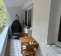 Glazed balcony of a 4-room apartment with seating and a hanging chair.
