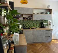 A kitchen in a 4-room apartment with wooden flooring and green tiles.