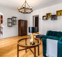 Living room in a 2-room apartment with a sofa, chandelier, and parquet flooring at the entrance to the kitchen.