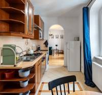 A kitchen with a wooden cabinet, a dining table, and a window with blue curtains in a 2-room apartment.
