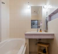 A bathroom in a 2-room apartment with a bathtub and a sink with purple tiles.