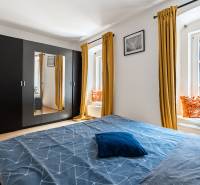 Bedroom with a large wardrobe, bed, and yellow curtains in a 2-room apartment.