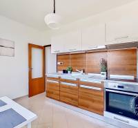 A kitchen with wooden paneling in a studio apartment, equipped with appliances and a dining table.