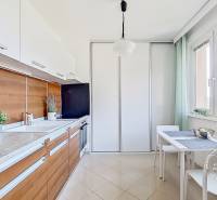 Kitchen in a studio apartment, white furniture, wooden details, spacious window.