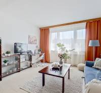 Living room with a sofa and a table in a studio apartment, with windows and curtains.