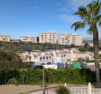 A view of residential buildings, trees, and containers on Aquiles Street in Torrevieja.