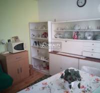 Interior of a family house with retro furniture, a microwave, and a dining table with a floral tablecloth.