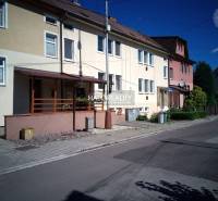 A family house in Nováky with a front garden and a paved walkway along the road.