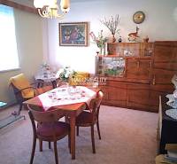 Interior in a family house, dining room with retro furniture, window, flowers, tablecloth, armchair.