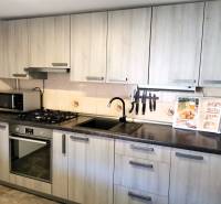 A kitchen in a family house with wood decor, a cooktop, and a stainless steel sink.