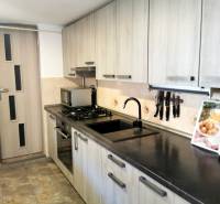 A kitchen in a family house with a wooden cabinet, a black sink, and a stove.