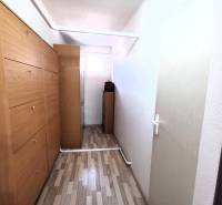 A hallway in a family house with wooden cabinets and white walls.
