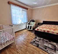 A room in a family house with a sofa, a crib, and a recliner.