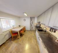 A kitchen in a family house with a dining table, a gas stove, and kitchen cabinets.