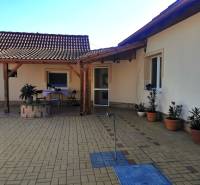 A family house in Veľké Kosihy with a paved yard and a shelter, plants in pots.