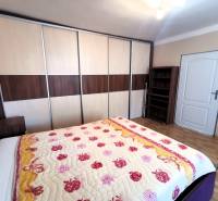 A bedroom in a family house with a large wardrobe and a bed with a colorful blanket.