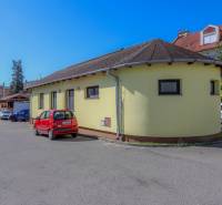 The yellow building on Slovenského národného povstania Street in the town of Vrbové with a parked red car.