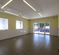 Interior of commercial spaces with tiled floors, white walls, and large windows.