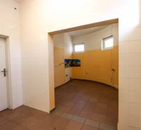 Commercial space with white tiles, bright lighting, and orange interior walls.