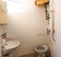 Bathroom in commercial premises with a shower, sink, and window.