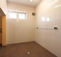 A tiled room with two windows and a fan in commercial premises.