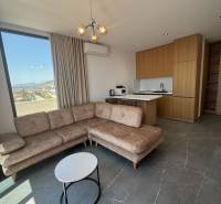 Living room of a holiday apartment with a corner sofa, view, and kitchenette.