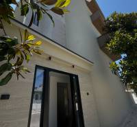 The facade of a holiday apartment in Ksamil, surrounded by greenery and a clear sky.