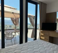Interior of a holiday apartment with a bed, wardrobe, and a terrace with a sea view.