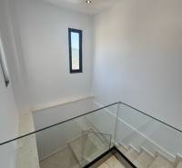 Staircase in a recreational apartment with large glass railing and narrow window.