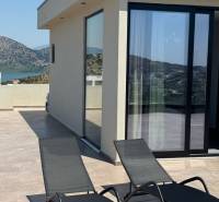 Terrace of a recreational apartment in Ksamil with a mountain view and two sunbeds.