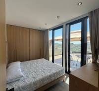 A bedroom in a holiday apartment with a view from the balcony, wooden furniture, and a bed.