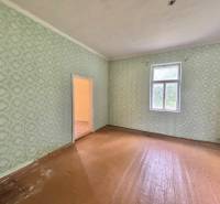 A spacious room in a family house with wallpaper and wooden flooring.
